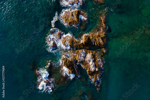 Aerial view of rocks under turquoise water