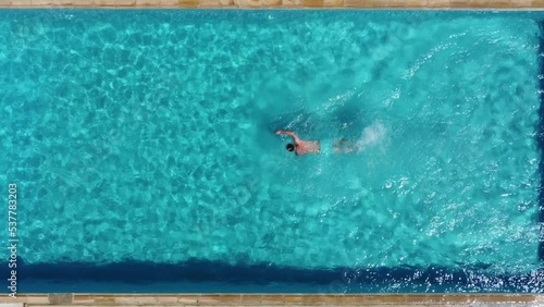 A man swims in a blue pool top view