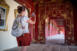Turista descubriendo los pasillos y corredores de la antigua ciudad imperial de Hue, mientras toma fotografías con su celular.	