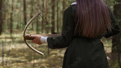 woman in long dress walks in forest with crossbow in hands, historical reconstruction, Middle Ages photo