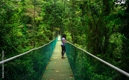 Young girl on suspension bridge with forest background in Central America