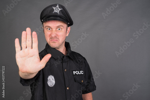 Portrait of Caucasian man wearing police uniform costume showing STOP gesture
