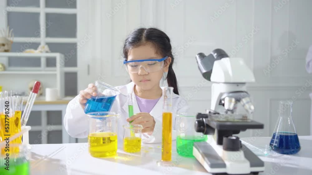 Portrait junior scientists practicing science in a lab. Excited child mixing chemical ingredients one by one doing experiment during a lesson Portrait junior scientists practicing science in a lab. Excited child mixing chemical ingredients one by one doing experiment during a lesson