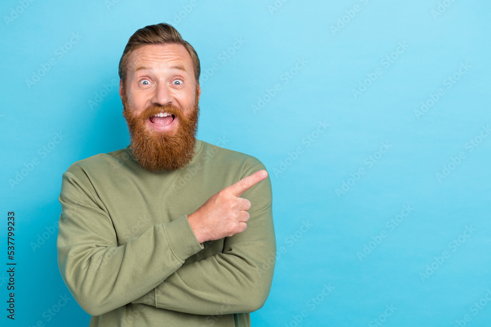 Photo of speechless staring crazy man with red hairstyle dressed khaki long sleeve directing empty space isolated on teal color background Photo of speechless staring crazy man with red hairstyle dressed khaki long sleeve directing empty space isolated on teal color background