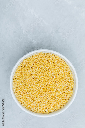 Millet. Organic raw dry Millet grains in bowl on gray stone background