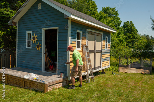 Man painting the exterior of a backyard shed photo