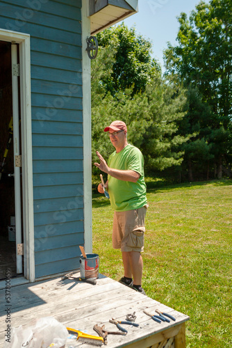 Man painting the exterior of a backyard shed