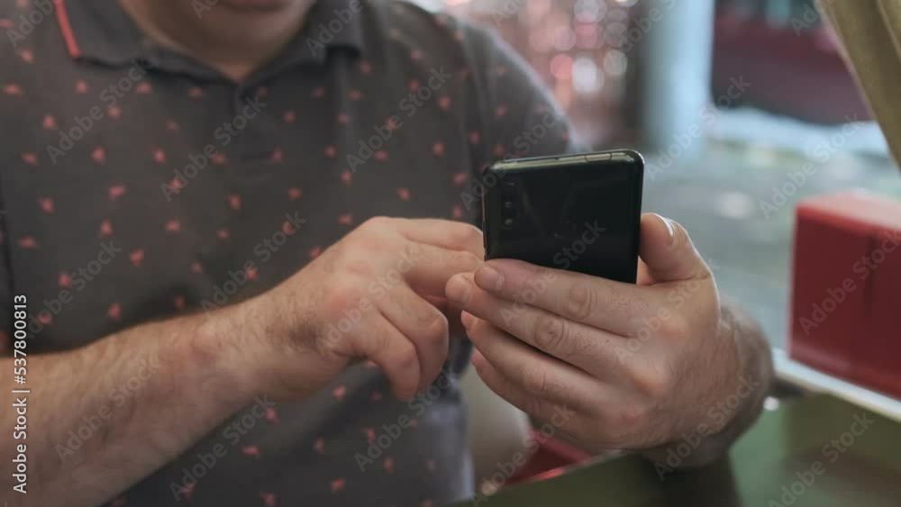 Men holding cell phone using smartphone device in a street cafe. Man blogger subscribing new social media, buying in internet, ordering products online in apps. Men holding cell phone using smartphone device in a street cafe. Man blogger subscribing new social media, buying in internet, ordering products online in apps.