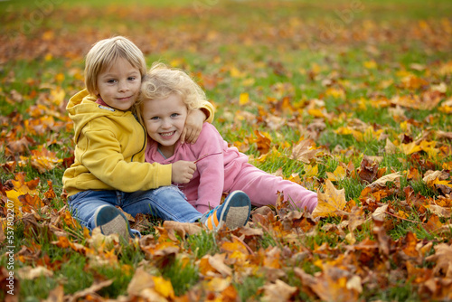 Cute blond toddler children boy and girl,walking in autumn park on sunset, enjoying the beautiful nature