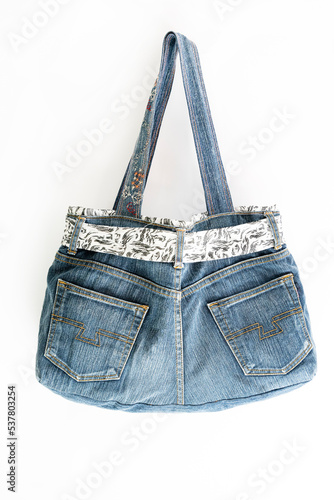 Denim bag made from old jeans hanging over white background