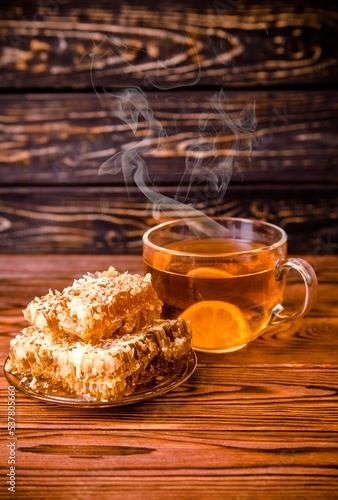honey in honeycombs and a mug of tea on a brown wooden background 