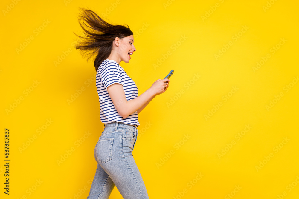 Profile side photo of funky satisfied lady arm hold use modern device gadget go empty space isolated on yellow color background Profile side photo of funky satisfied lady arm hold use modern device gadget go empty space isolated on yellow color background