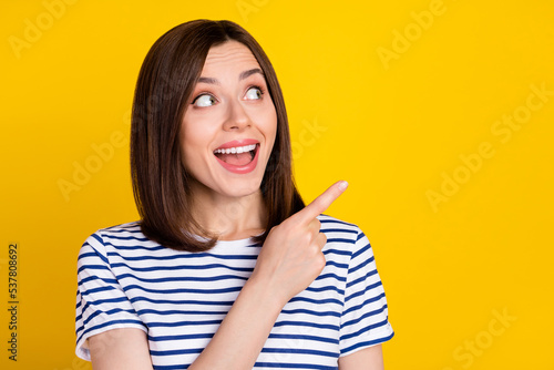 Portrait of cute gorgeous positive girl wear striped t-shirt directing empty space open mouth isolated on yellow color background