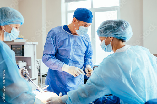 Surgeons team during preparation for surgery before performing operation in hospital operating theatre, male and female surgeon operating patient working with surgical gynecology equipment.