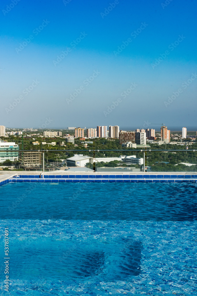 Barranquilla, Atlantico, Colombia. July 30, 2022: Swimming pool from a building and view towards the city with beautiful blue sky.