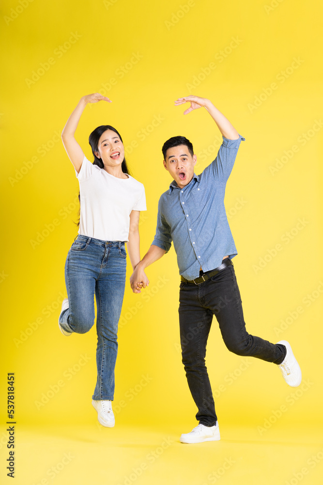 full body image of asian couple posing on yellow background full body image of asian couple posing on yellow background
