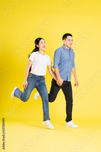 full body image of asian couple posing on yellow background