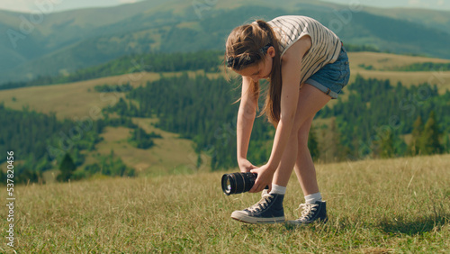 Young photographer filming beautiful movie. Girl creating content in motion, wathing results and feeling happy, spending leisure time outdoor photo