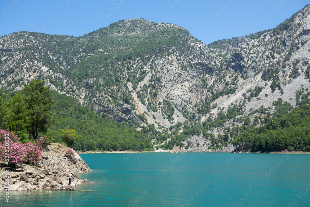 Manavgat, Turkey - June 05, 2019: A fisherman catches fish on a lake among mountain cliffs in the Green Canyon