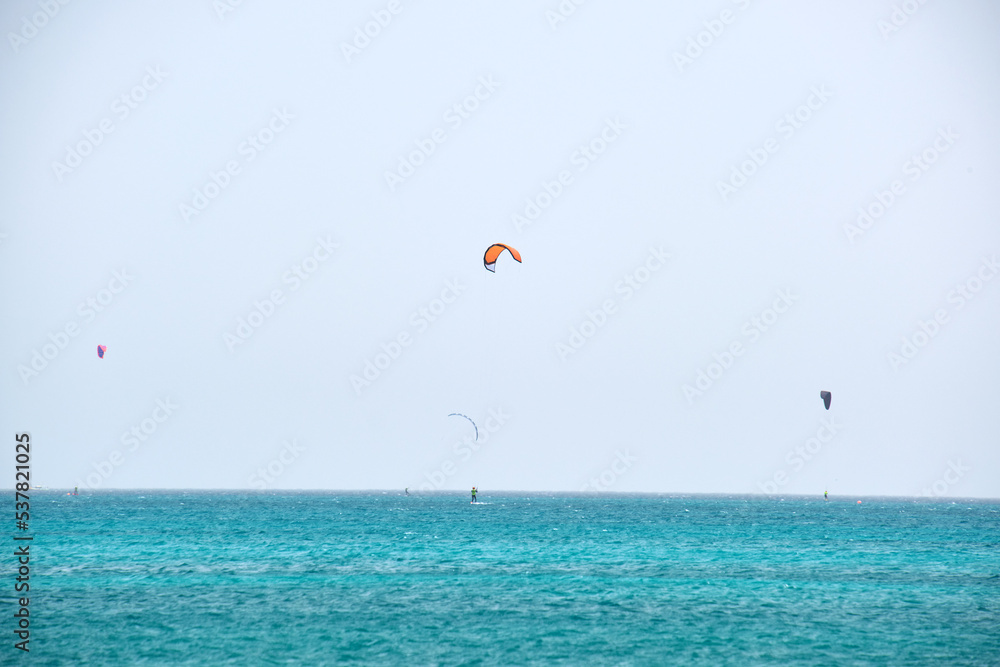 People sportsmen windsurfing and kite surfing in blue ocean water. Summer extreme exotic sport concept People sportsmen windsurfing and kite surfing in blue ocean water. Summer extreme exotic sport concept