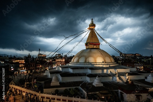 Aerial view of Boudhanath Stupa temple dome with prayer flags under dark cloudy stormy sky photo