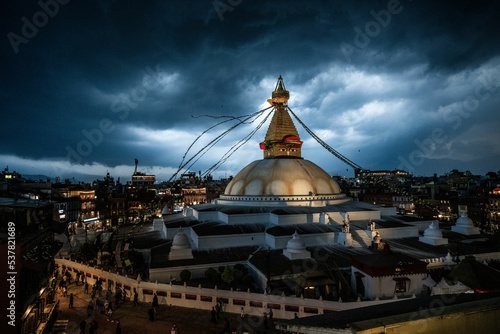 Aerial view of Boudhanath Stupa temple dome with prayer flags under dark cloudy stormy sky photo