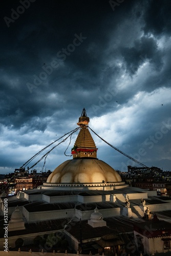 Aerial view of Boudhanath Stupa temple dome with prayer flags under dark cloudy stormy sky photo