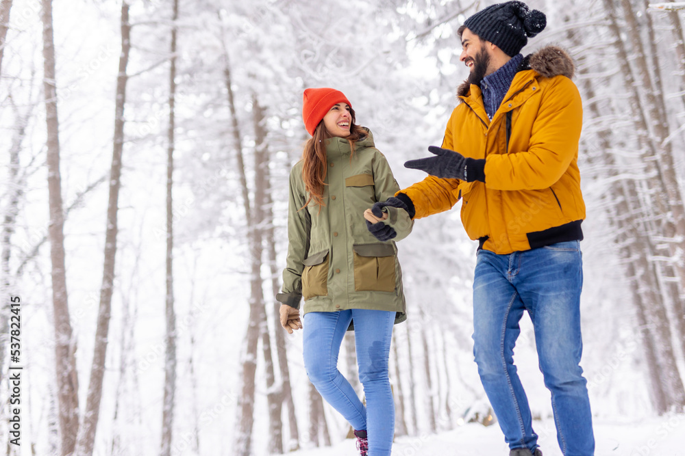 Couple taking a walk through a forest on snowy winter day Couple taking a walk through a forest on snowy winter day