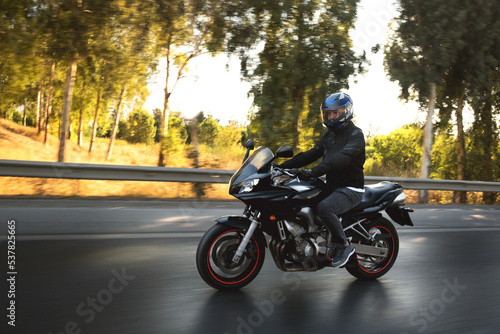 Side view of a biker riding on the road with motion blur. © ardasavasciogullari