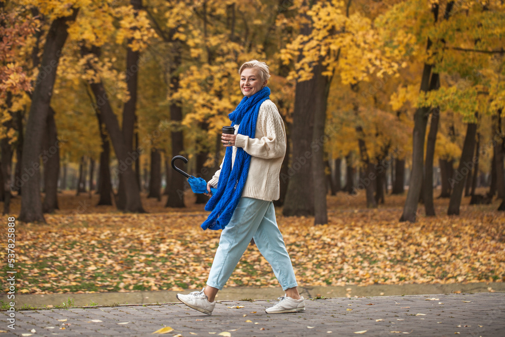 Fototapeta premium Beautiful middle-aged woman walking in autumn park