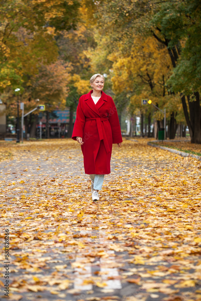 Portrait of a beautiful middle-aged woman in a red coat, autumn park Portrait of a beautiful middle-aged woman in a red coat, autumn park