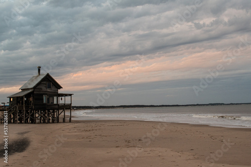 wooden house on the beach at sunset photo