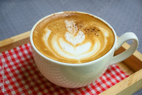 Coffee in white cup on wooden table in cafe with lighting background.