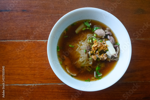Asian delicatessen, beef noodles with soup on wood table.