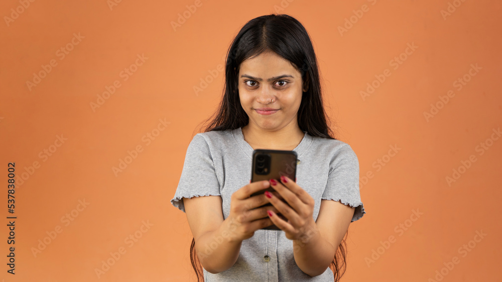 Cheerful young woman holding smartphone isolated over color background Cheerful young woman holding smartphone isolated over color background