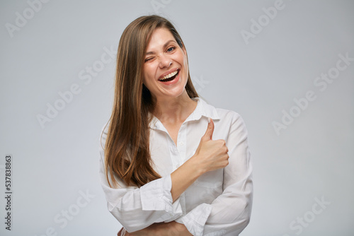 Portrait of winking woman showing thumb up. Girl with big wide smile.