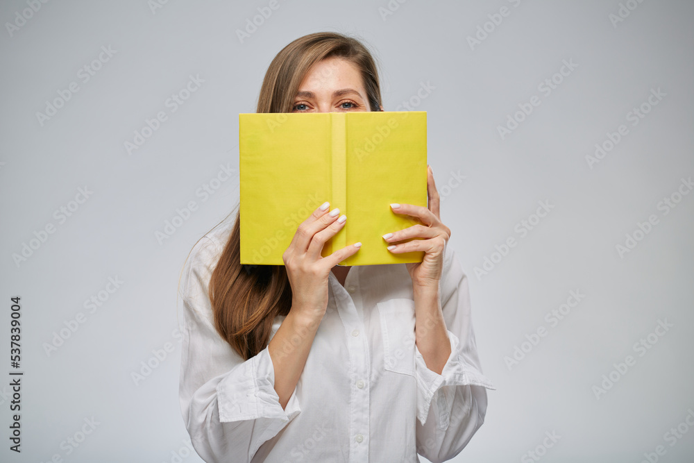 Woman covering her face with yellow book, isolated female portrait. Woman covering her face with yellow book, isolated female portrait.