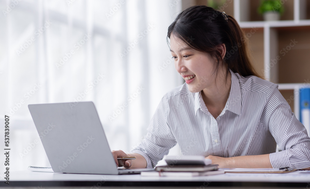 Attractive and charming Young asian woman working on laptop in modern office Attractive and charming Young asian woman working on laptop in modern office