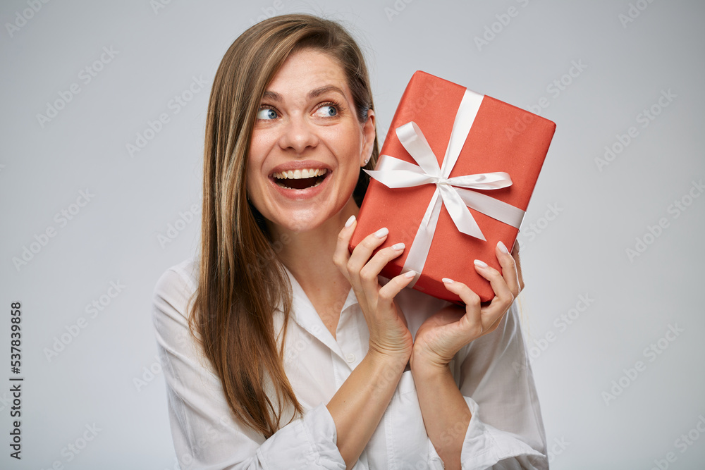 Smiling happy woman holding gift box looking up. Isolated female portrait. Smiling happy woman holding gift box looking up. Isolated female portrait.