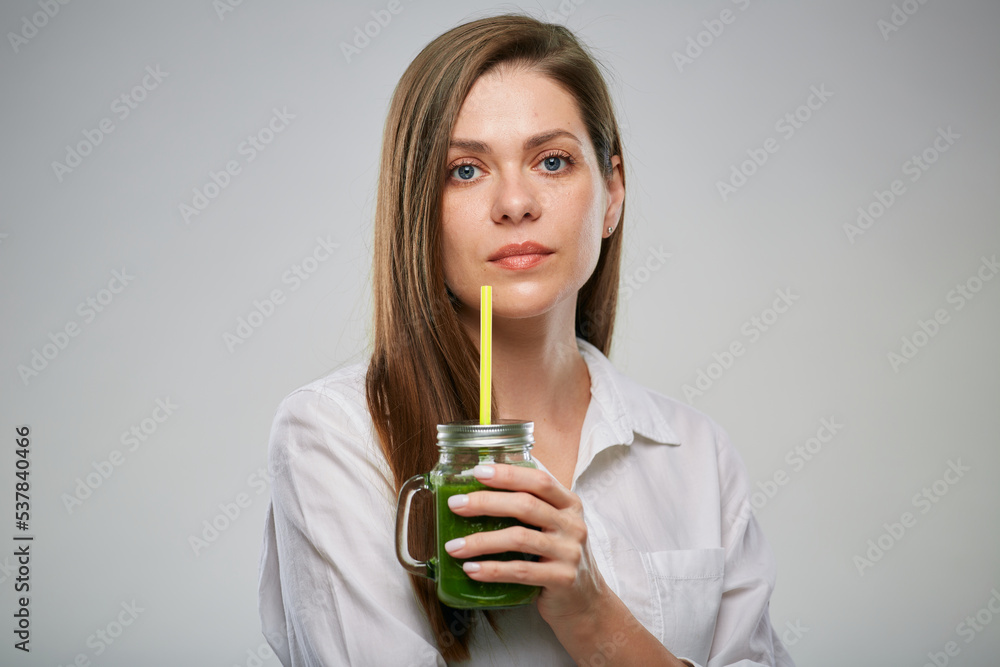 Woman in white shirt holding green smoothie in jar with straw. Isolated female advertising portrait. Woman in white shirt holding green smoothie in jar with straw. Isolated female advertising portrait.