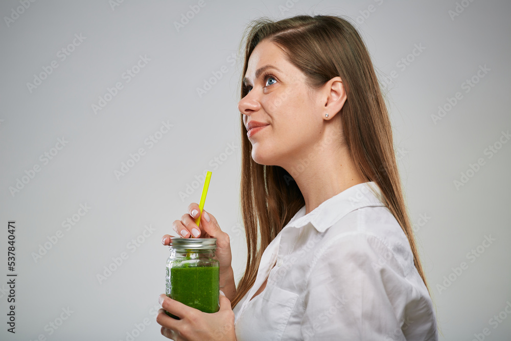 Profile view of smiling woman drinking green smoothie and looking up. Isolated female advertising portrait. Profile view of smiling woman drinking green smoothie and looking up. Isolated female advertising portrait.