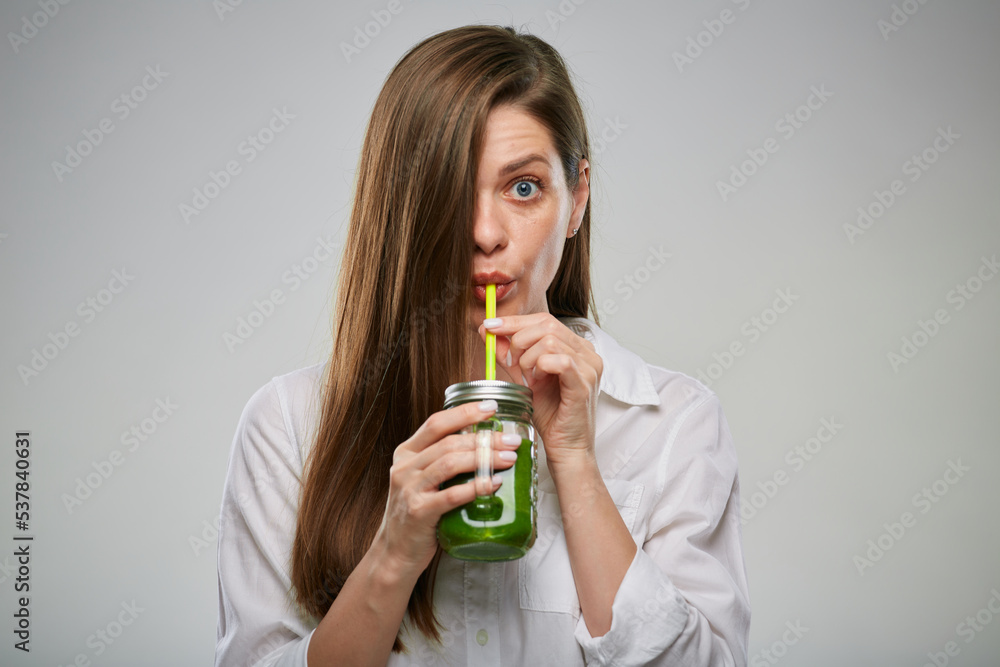 Young woman drinking green smoothie from glass jar. Isolated advertising female portrait. Young woman drinking green smoothie from glass jar. Isolated advertising female portrait.