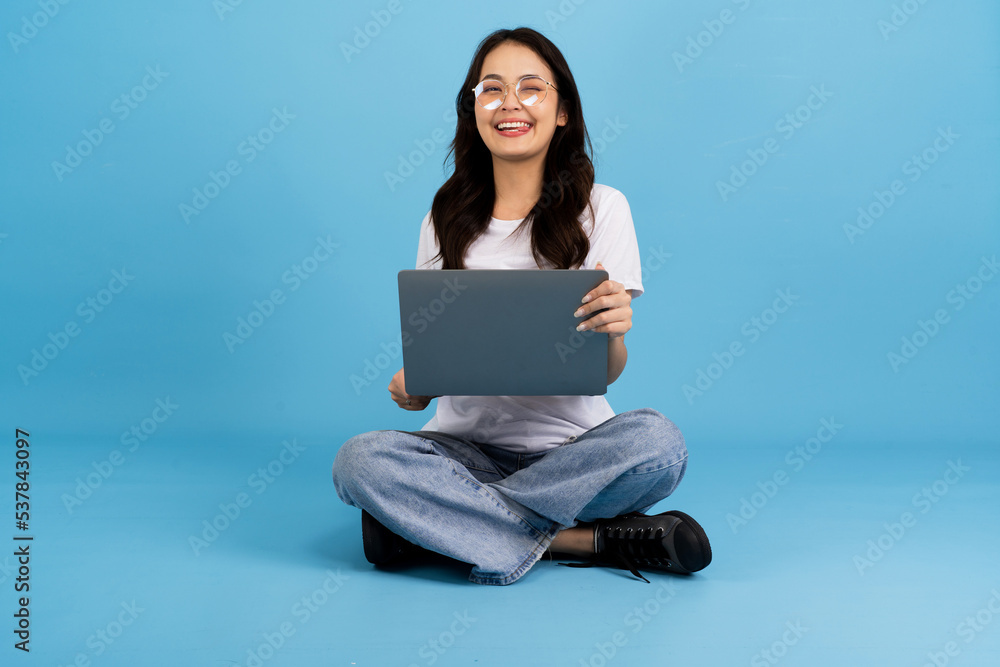 Beautiful girl happy holding a notebook computer sitting on a blue. Beautiful girl happy holding a notebook computer sitting on a blue.
