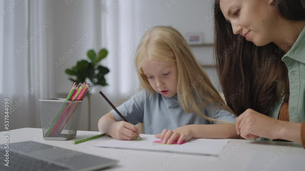 Mom helps her little daughter do her homework. Mom teaches the girl to draw. Home training, online training. Mom helps her little daughter do her homework. Mom teaches the girl to draw. Home training, online training.