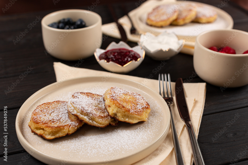 Cheesecakes, Saxon cottage cheese on a plate, with topping options in the form of fresh berries, sour cream and jam