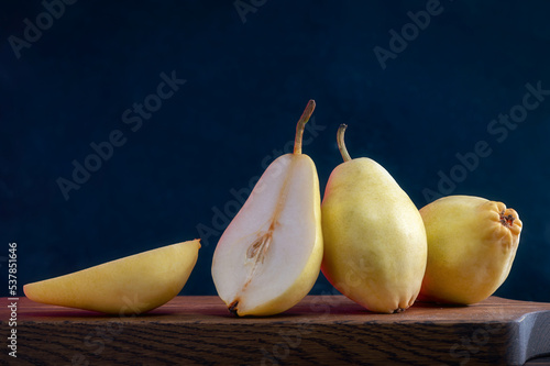 Two Whole And One Cut Pears Lie On A Wooden Board. Healthy Food. Eco-Friendly Products. Selective Focus. Side View. Dark Background.