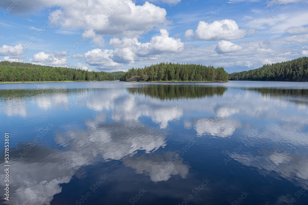 View to Hermusenlahti lake from Talas Campfire Site in Repovesi National park on beautiful summer day. White clouds reflecting in blue calm water
