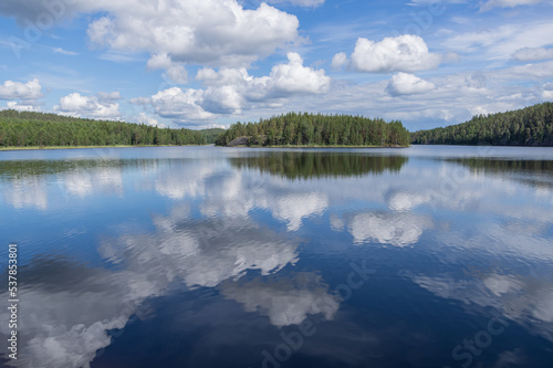 View to Hermusenlahti lake from Talas Campfire Site in Repovesi National park on beautiful summer day. White clouds reflecting in blue calm water 