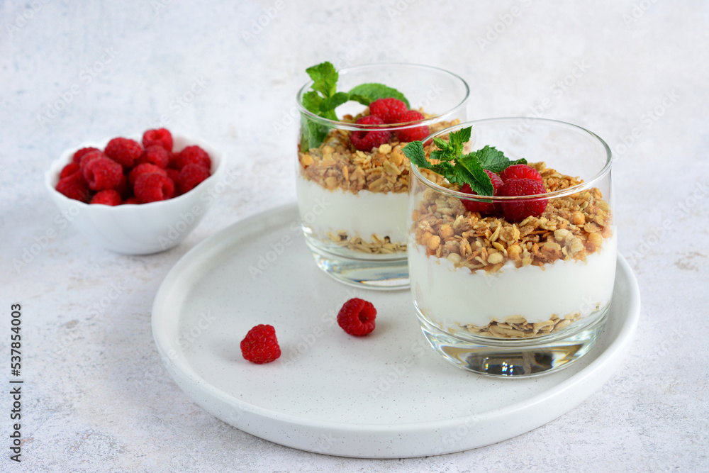 healthy breakfast with yoghurt, muesli and raspberry in glass on white tray, close-up healthy breakfast with yoghurt, muesli and raspberry in glass on white tray, close-up