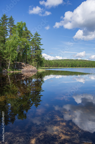 View to Hermusenlahti lake from Talas Campfire Site in Repovesi National park on beautiful summer day. White clouds reflecting in blue calm water